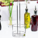 A Tablecraft chrome metal rack holding olive oil cruets and flowers on a table.