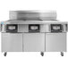 A large commercial kitchen with stainless steel equipment including a Frymaster electric floor fryer with three frypots.
