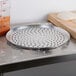 An American Metalcraft heavy weight perforated aluminum pizza pan with a dough ball on it.