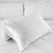A white Oxford Standard Size Waterproof Zippered Pillow Protector on a white pillow on a bed.