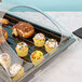A Cambro clear dome display cover over a tray of cupcakes and pastries.