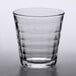 A clear Duralex glass tumbler with a patterned curved edge.