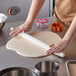 A person using an Ateco Tapered French Rolling Pin to roll out dough on a counter.
