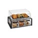 A Vollrath Cubic clear acrylic pastry display case with black frame full of bread and pastries.