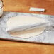 A white marble Fox Run French rolling pin on a marble board.