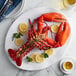 A Boston Lobster Company lobster on a plate with lemon slices and herbs.