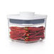 A clear OXO Good Grips square food storage container with red peppers inside and a white lid.