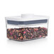 A clear OXO food storage container filled with dried flowers and leaves with a white lid.