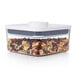 An OXO Good Grips plastic food storage container with nuts and seeds inside.
