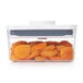 A plastic container with dried apricots inside.