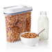 An OXO plastic food storage container with cereal in it on a white background.