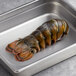 A Boston Lobster Company 12-14 oz. lobster tail in a metal pan.