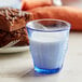 A close-up of a Duralex marine glass filled with milk on a table with brownies.