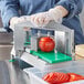 A person using a Garde XL tomato slicer to cut tomatoes on a counter.