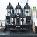 A Bunn universal airpot rack holding five coffee containers.