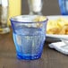 A close-up of a Duralex marine blue glass filled with water on a table.