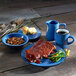 A table with a Campfire Ocean Blue stoneware plate of food and a blue bowl of beans.