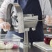 A woman using a Choice Prep ROTOSLICE machine to cut a red onion on a white cutting board.