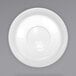 A white porcelain saucer with a circular design on a gray background.