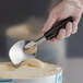 A hand using a Vollrath stainless steel ice cream spade to scoop ice cream.