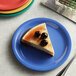 A piece of cheesecake with cherries on top on a blue Elite Global Solutions melamine plate.