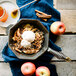 An apple crisp in a FINEX cast iron skillet with ice cream and cinnamon.