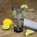 A Carlisle Louis smoke plastic tumbler filled with water, ice, and lime slices.