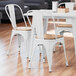 A Lancaster Table & Seating white chair with a natural wood seat at a table in a restaurant.
