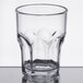 A Carlisle clear plastic tumbler with a rim on a table.