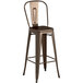 A brown metal Lancaster Table & Seating bar stool with a natural wood seat.