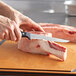 A person using a Wusthof Gourmet boning knife to cut meat on a cutting board.