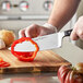 A person using a Wusthof Classic Wide Cook's Knife to slice a red bell pepper.