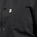 A close-up of a black Uncommon Chef short sleeve cook shirt with a white pocket.