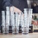 A woman stacking clear Acopa Select Old Fashioned glasses on a table.