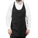 A man wearing a black Uncommon Chef tuxedo apron with 3 pockets.