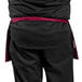 A person wearing a burgundy Uncommon Chef waist apron with black trim.