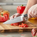 A person uses a Wusthof Classic Cook's Knife to cut tomatoes on a cutting board.