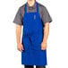 A man wearing a Uncommon Chef royal blue apron with three pockets.