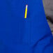 A pencil in one of the three pockets of a royal blue Uncommon Chef bib apron.