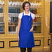 A woman wearing a royal blue Uncommon Chef bib apron.