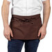 A man wearing a brown Uncommon Chef waist apron with 3 pockets.