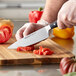 A person using a Wusthof Classic Ikon Cook's Knife to cut tomatoes on a cutting board.