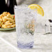 A Carlisle Alibi plastic glass of water with ice and a lemon wedge.