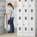 A woman standing in a locker room in front of Regency Space Solutions 3 wide, 2 tier lockers.