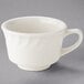 A Tuxton white china short cup with an embossed swirl rim and a handle.