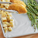A tray of food with Choice Non-Stick Aluminum Foil holding green beans and potatoes.