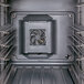 The interior of a black Cambro food holding cabinet with metal shelves and a fan.