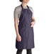 A woman wearing a navy blue Intedge bib apron with pockets.