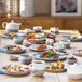 A white porcelain cappuccino cup with gray speckles on a table full of plates of food.