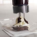 A brownie in a plastic container with chocolate syrup being poured on top using the Server ProPortion Handheld Triple-Tip Dispenser.